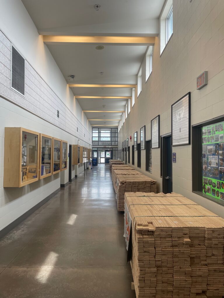 Hallway with pallets of maple hardwood ready to be installed in a new gym floor