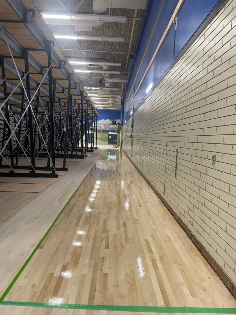 System to finish hardwood in new gym floor behind bleachers